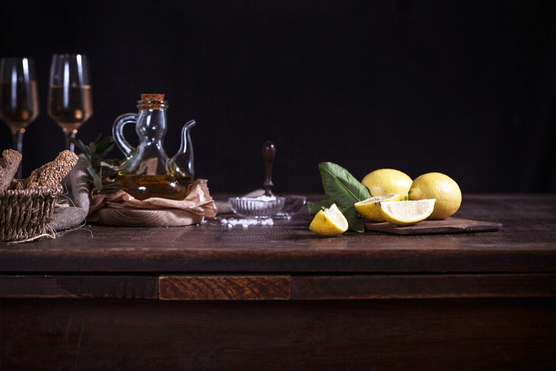 Zitronen, Olivenöl und Weißwein auf Holztisch