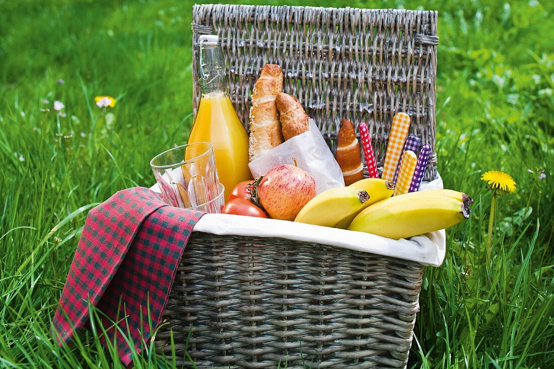 Picknickkorb mit Obst, Brötchen und Orangensaft