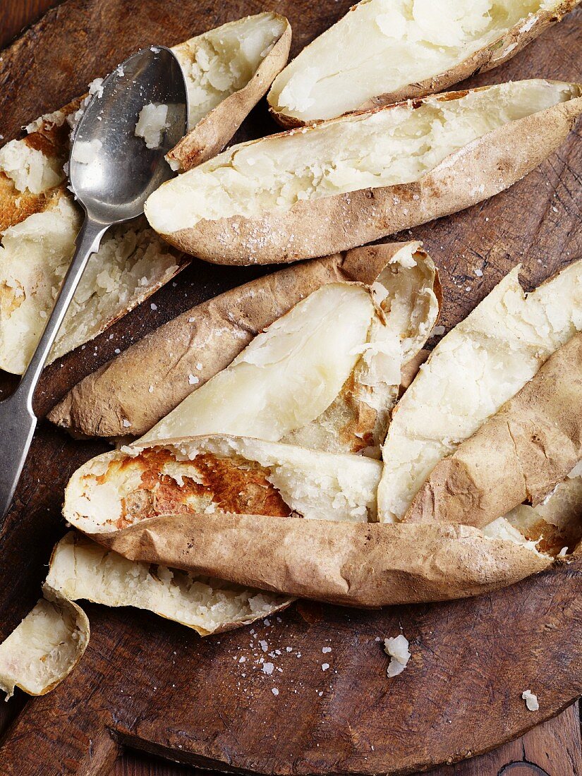 Scrapped out potato skins with a spoon on a wooden board