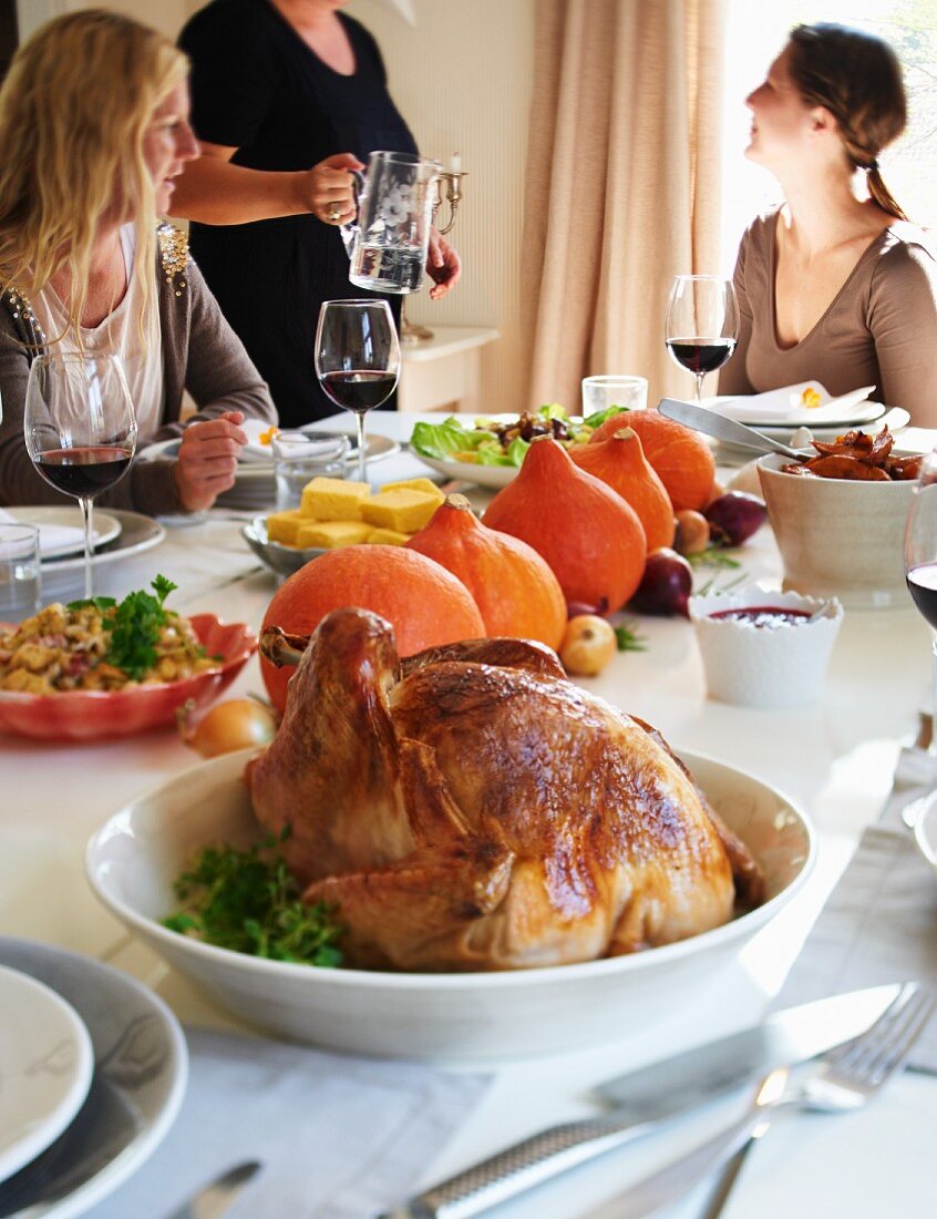 Gedeckter Tisch zu Thanksgiving mit gefülltem Truthahn, Kürbissen und Maisbrot