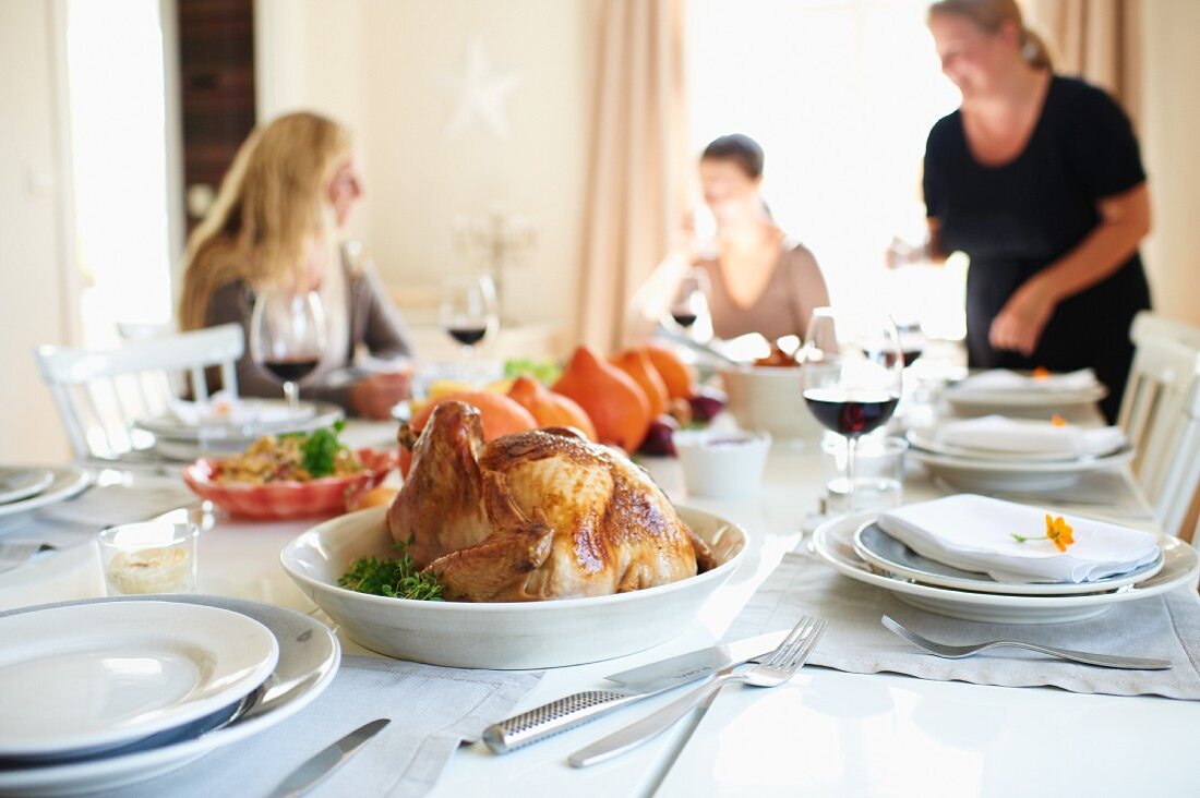 Gedeckter Tisch zu Thanksgiving mit gefülltem Truthahn, Kürbissen und Maisbrot