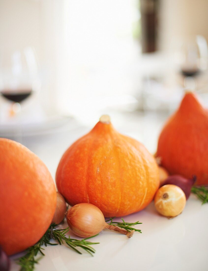 A table decorated for Thanksgiving: pumpkins, onions and rosemary