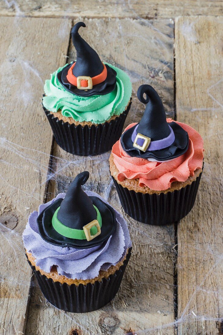 Three Halloween cupcakes decorated with witches hats