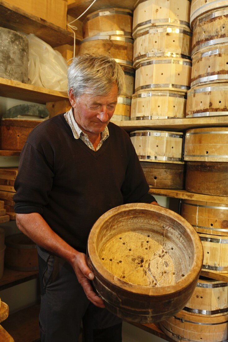 A man holding a wooden mould for making cheese