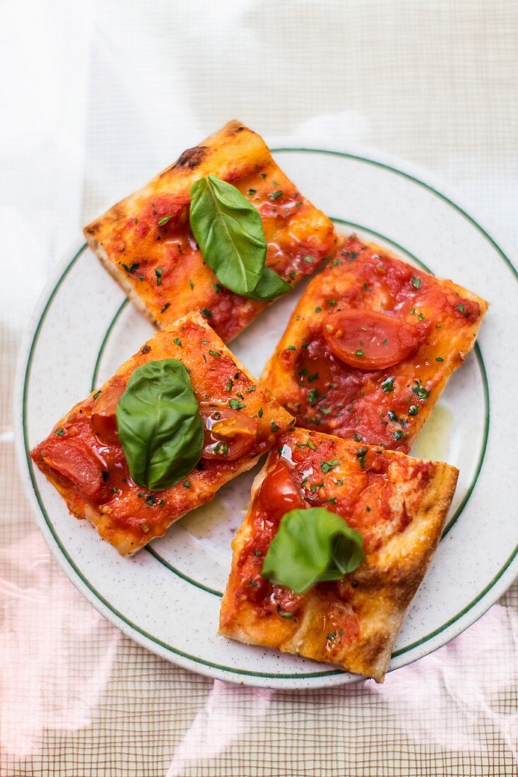 Kleine Pizzastücke mit Tomaten und Basilikum
