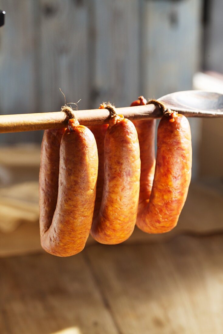 Sausages hanging on a wooden spoon