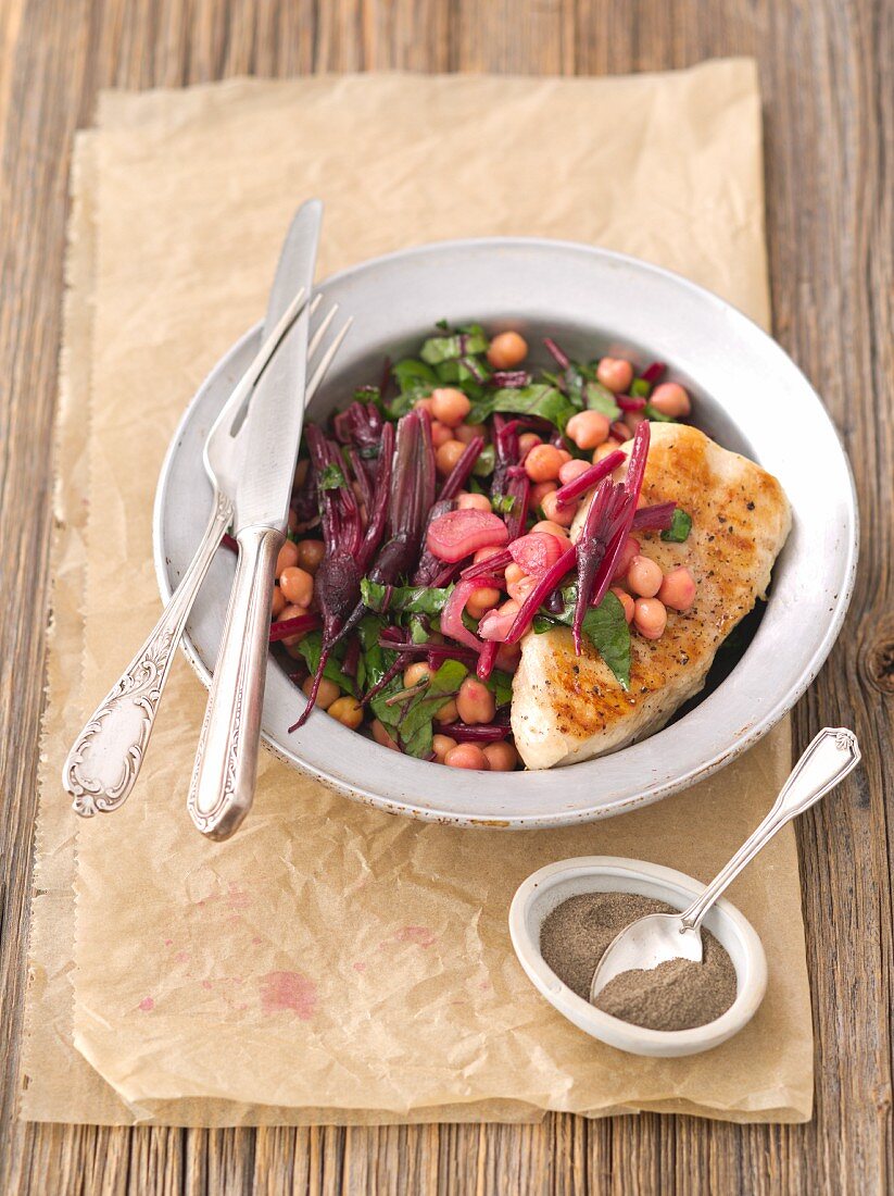 Warm chickpea salad with beetroot leaves and shallots served with grilled chicken breast