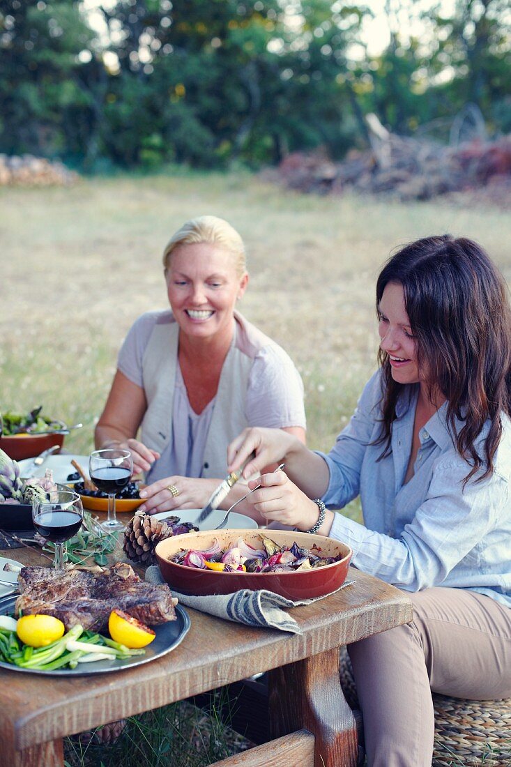 Two women eating Provençal food in a garden