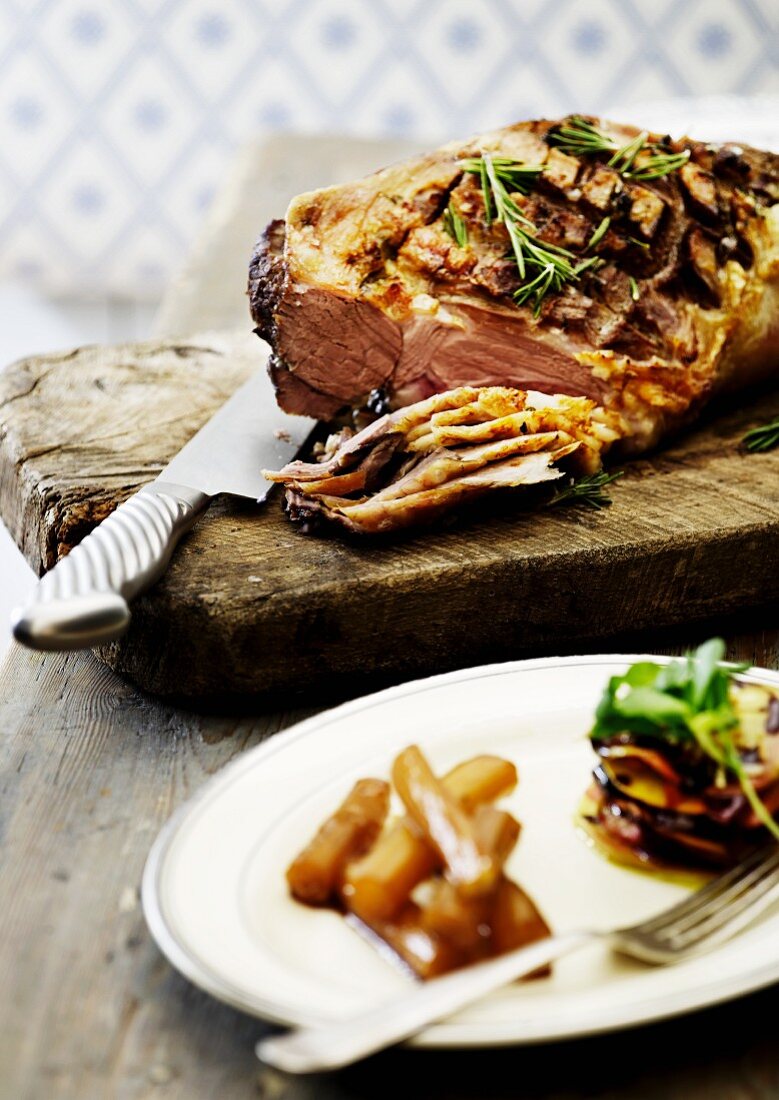 Crispy roast beef with a mustard crust on a chopping board, partially sliced
