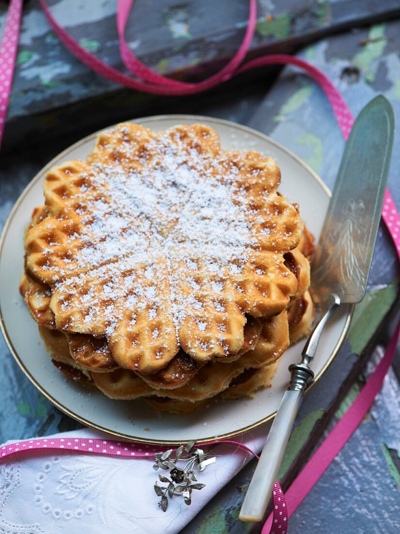 A stack of waffles with icing sugar