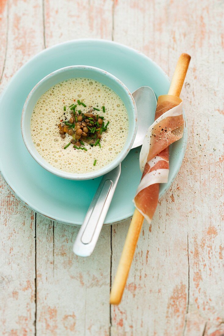 Foamy lentil soup and a breadstick wrapped in Parma ham