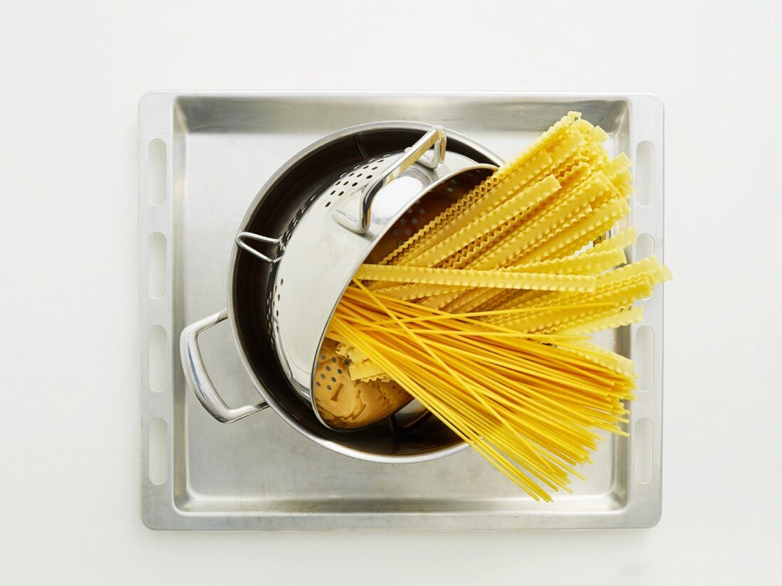 Pasta in a colander in a pot on a baking tray