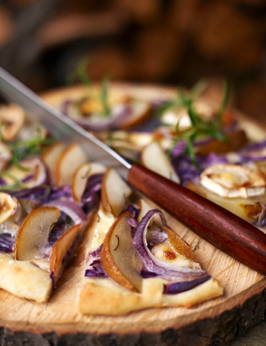 An autumnal pizza with pears, goat's cheese and red onions, sliced