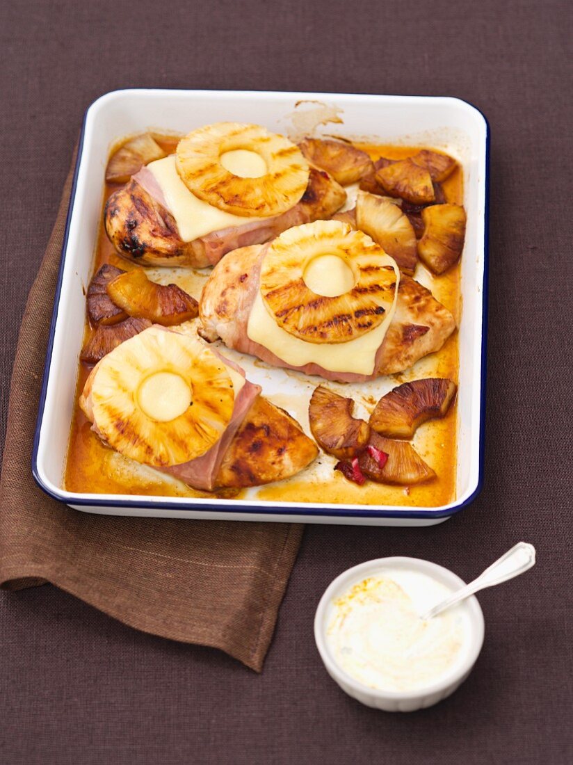 Baked chicken breasts wrapped in ham topped with cheese and pineapple