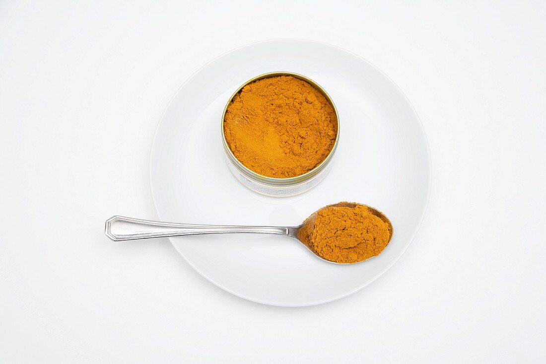 Madras-Currypulver in einer Dose und auf Löffel
