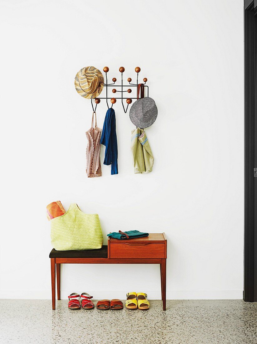 Sparsely furnished hallway with shoes below bench and hats and summer tops on classic coat rack (Hang it all)