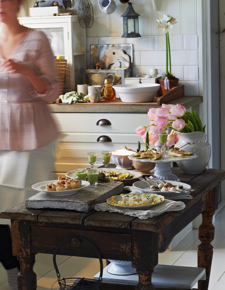 Festliches Buffet mit verschiedenen Häppchen auf rustikalem Holztisch in gemütlicher Küche im Landhausstil