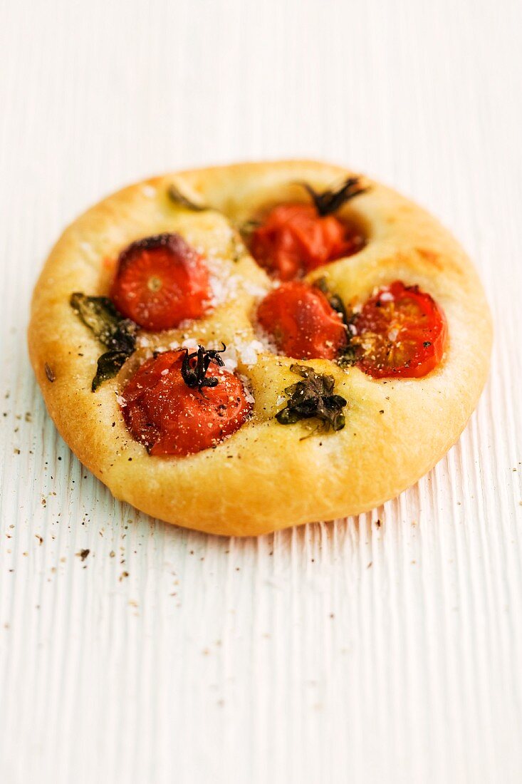 Focaccia with cherry tomatoes and basil on a wooden surface