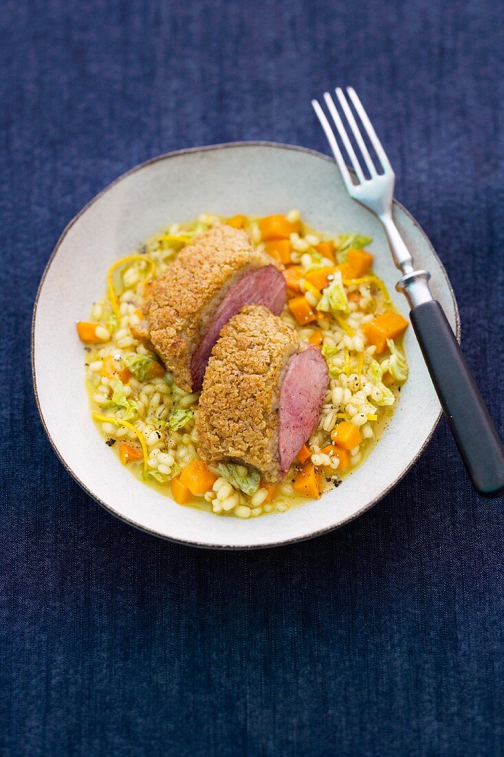 Coated duck breast on a bed of pearl barley with pumpkin