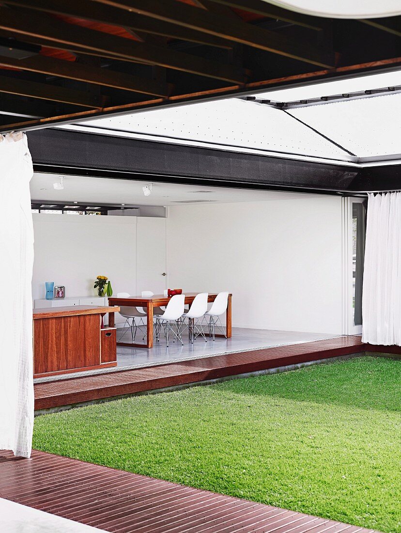 House with opening facades built around courtyard lawn with encircling boardwalk; view of dining area with classic chairs (DSW)