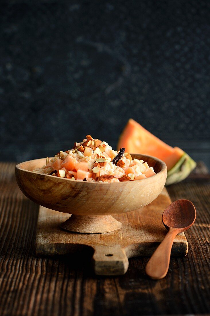 Rice pudding with melon and almonds in a wooden bowl