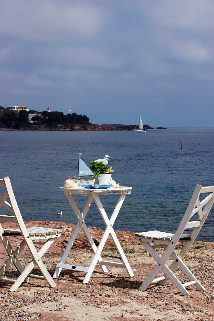 A table and chairs made from white painted wood on the beach