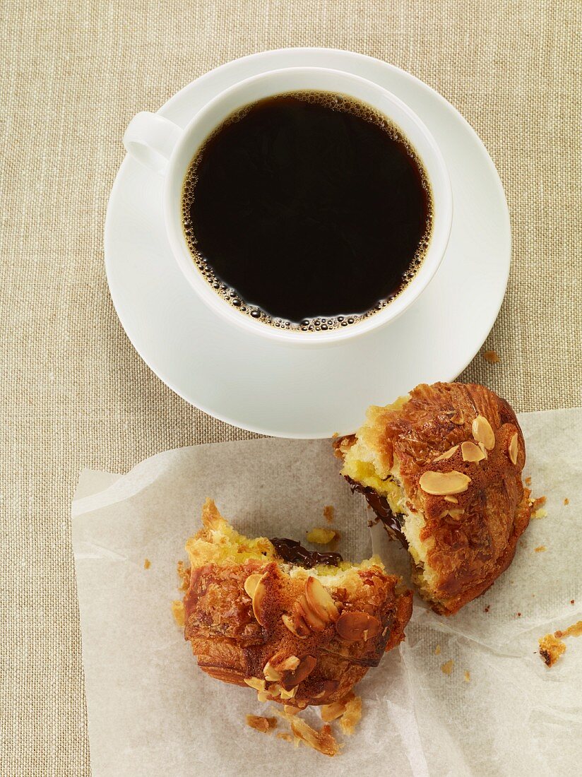 A cup of coffee and an almond croissant