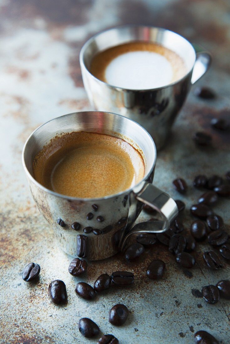 Espresso und Cappuccino auf Metalloberfläche mit Kaffeebohnen