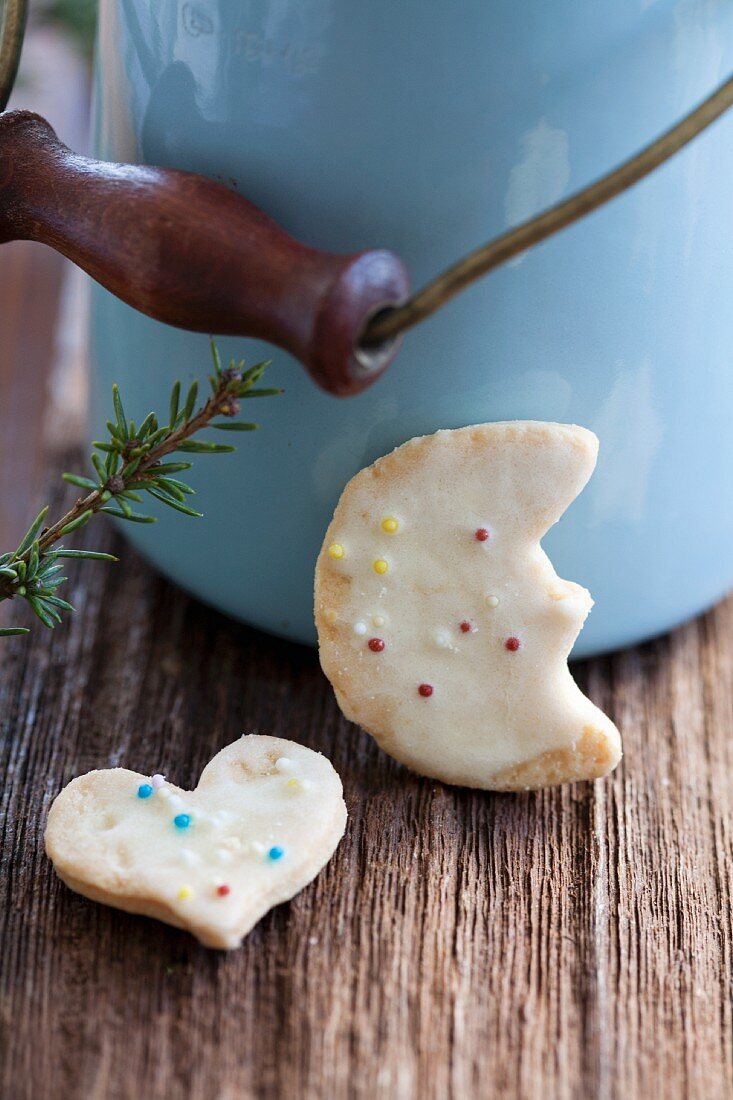 Butter biscuits decorated with coloured sprinkles in front of a milk churn