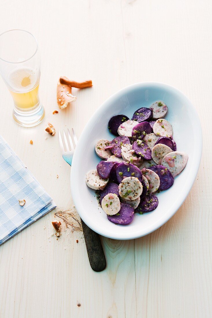 Potato salad made with purple and white potatoes served with a pretzel and beer