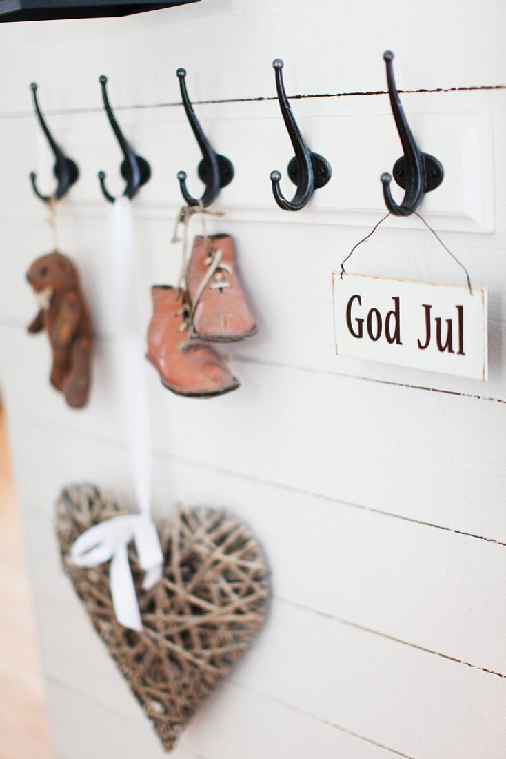 Vintage child's shoes and sign with motto hanging from coat pegs on white wooden wall