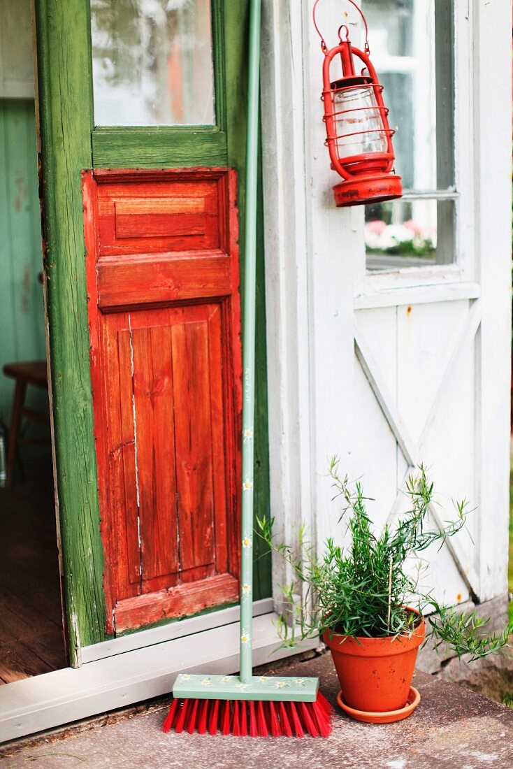 Hurricane lamp and broom outside front door painted in bright green and orange