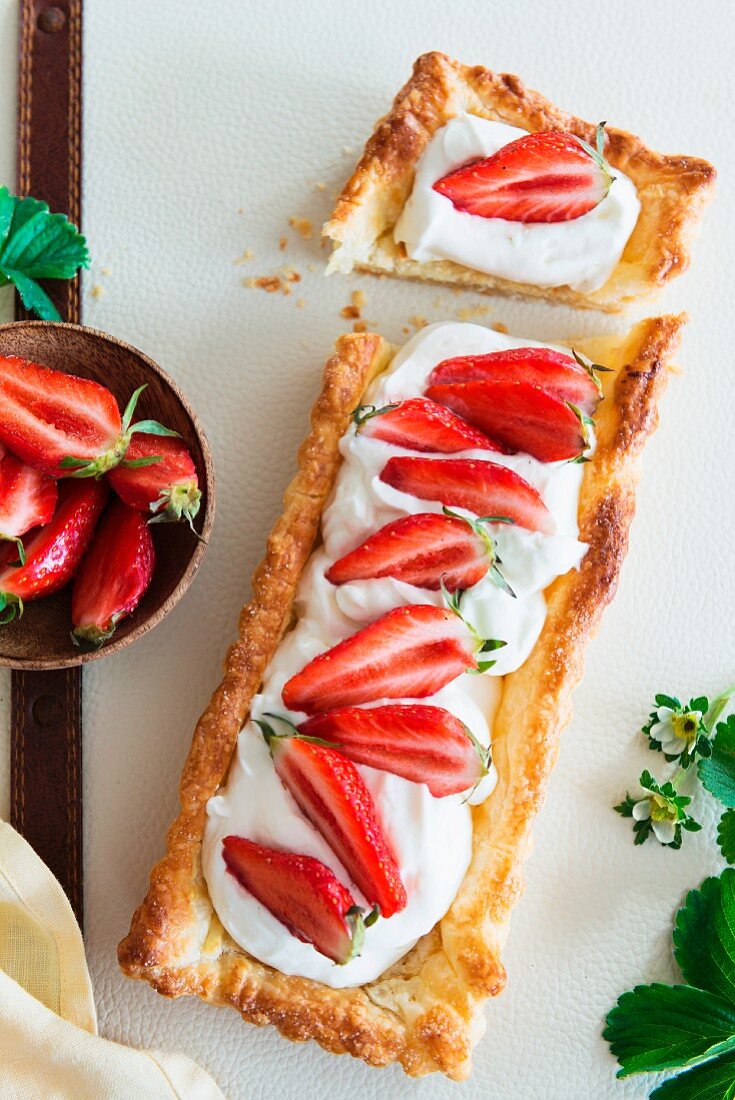 A puff pastry tart topped with yoghurt and strawberries, sliced