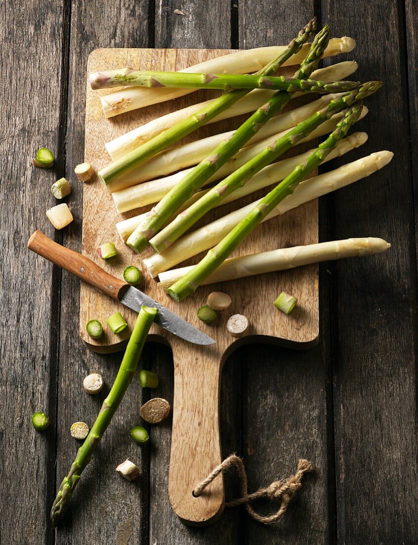 Weisser und grüner Spargel mit abgeschnittenen Endstücken auf Schneidebrett