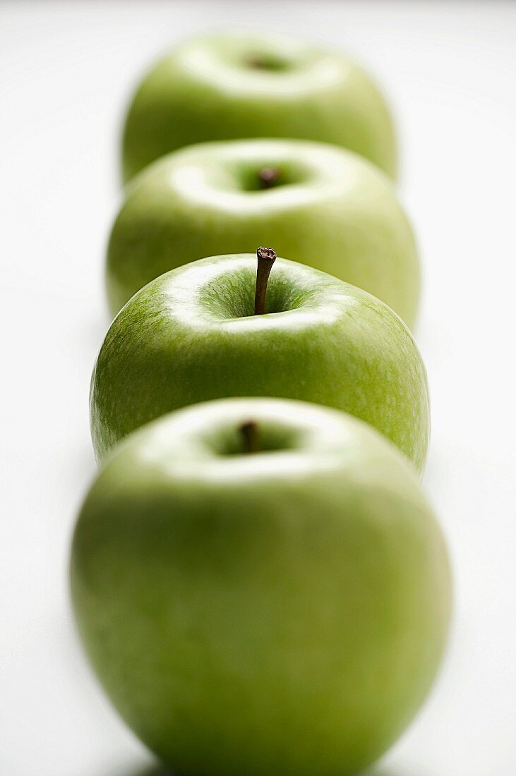 A row of four green apples
