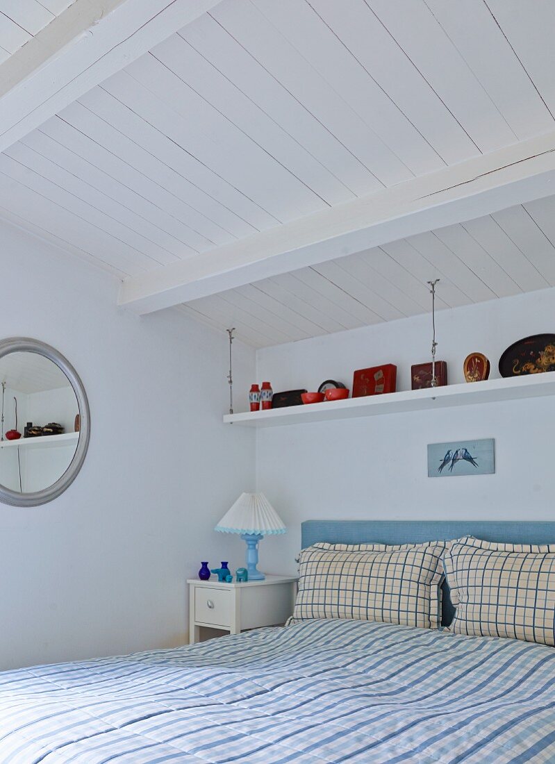 Double bed with gingham bed linen in rustic bedroom with white-painted wooden ceiling