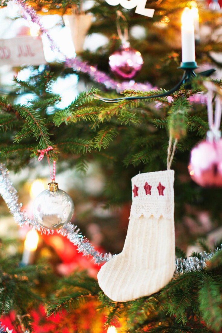 weiße Kindersocke mit Sternchen an geschmücktem Weihnachtsbaum