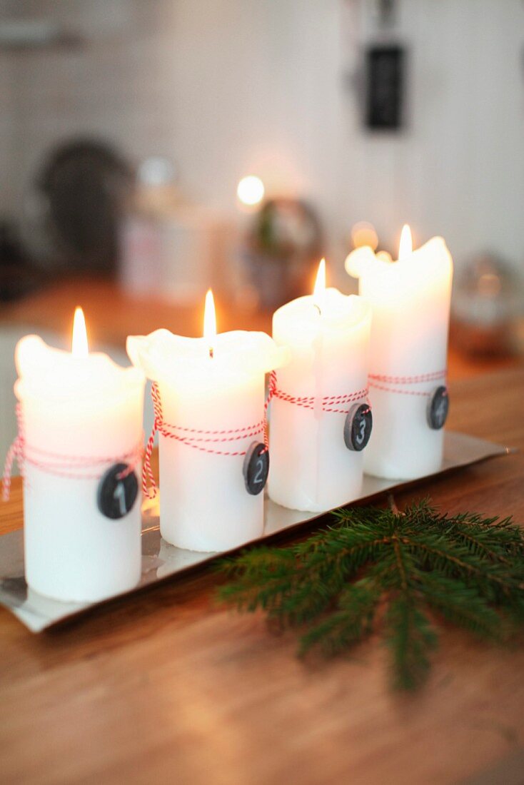 Lit white candles on metal tray