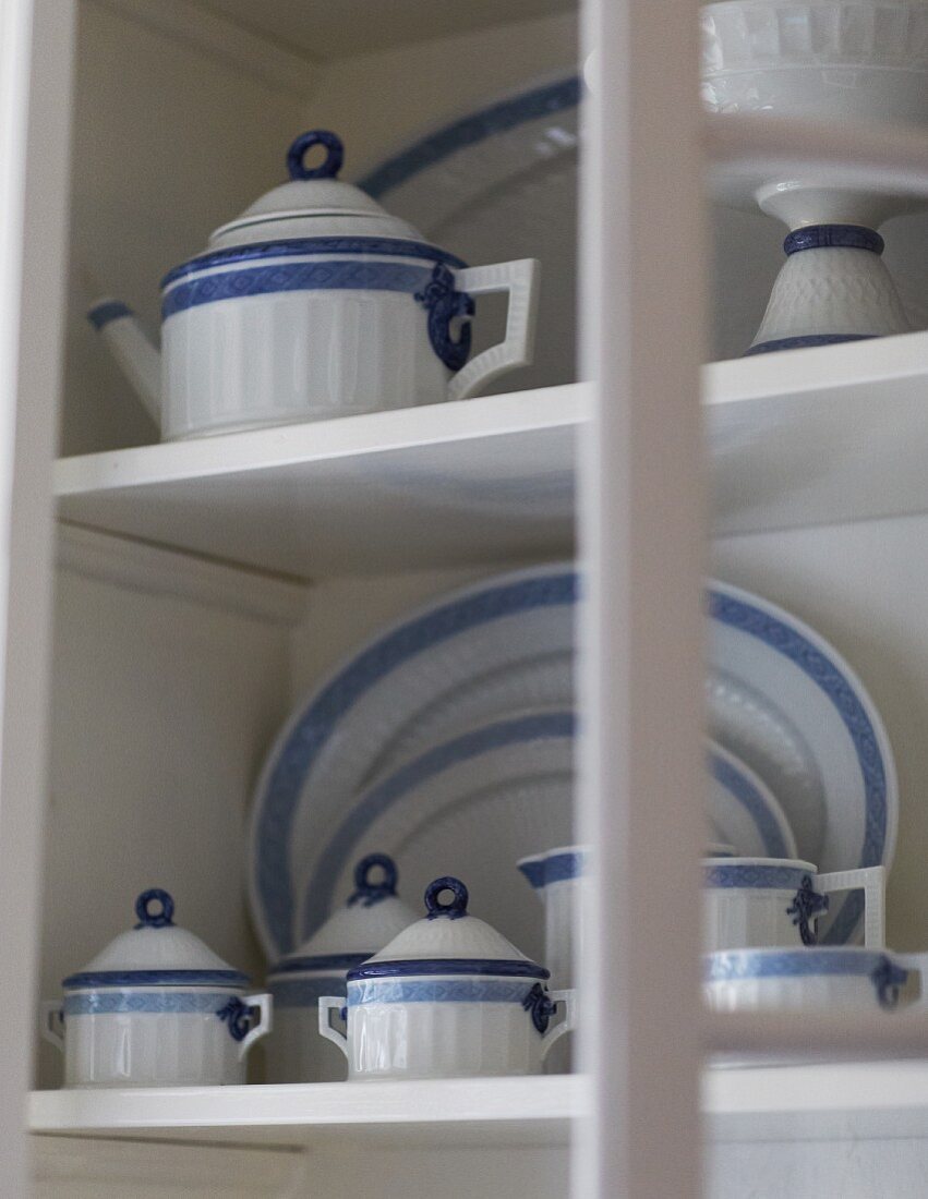 Weiß blaues Geschirr auf weissen Ablagen im Schrank