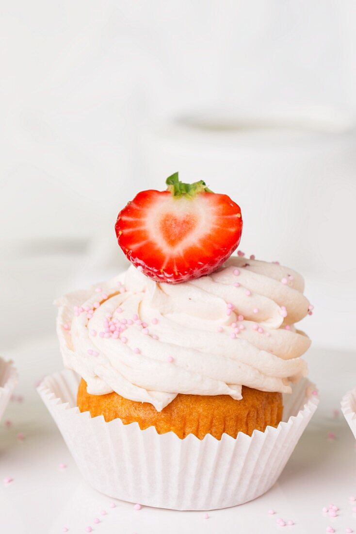 Ein Erdbeer-Cupcake mit rosa Zuckerperlen