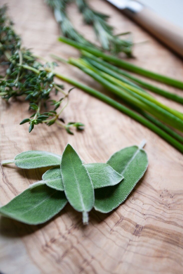 Fresh herbs on a wooden board (sage, thyme, chives and rosemary)
