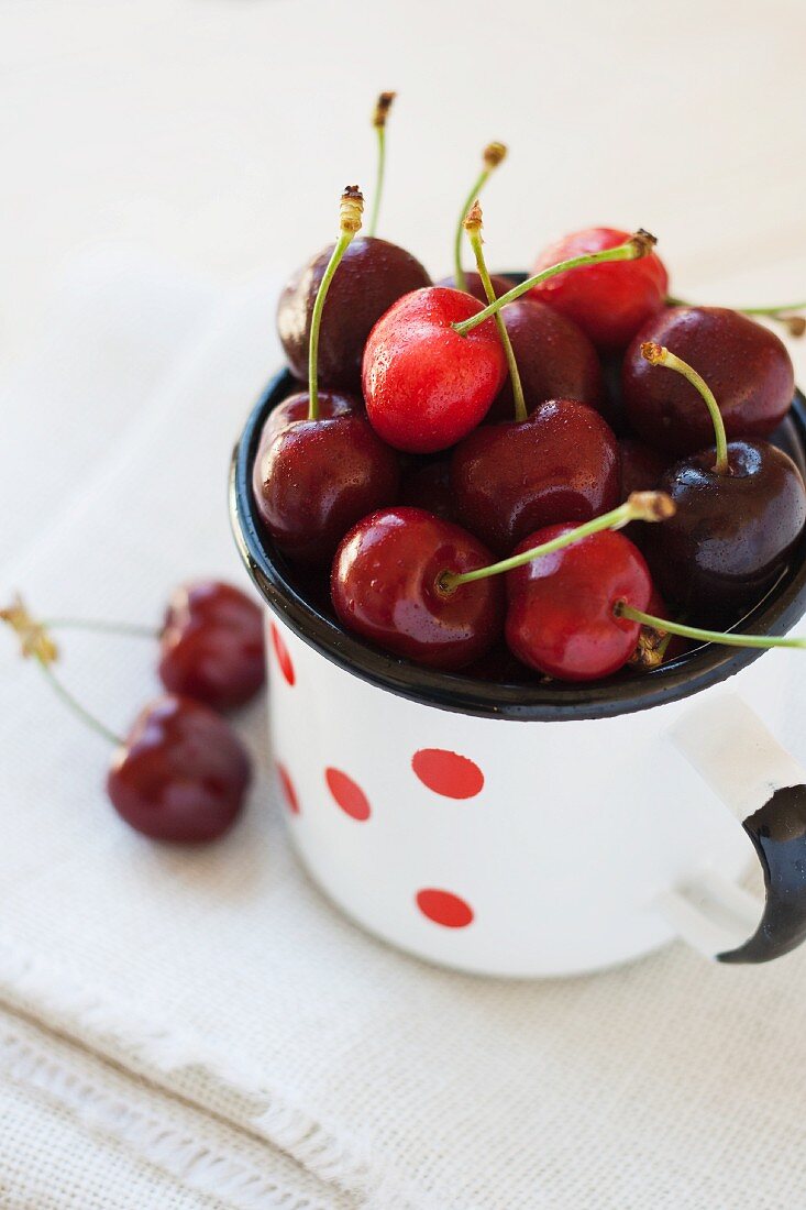 Cherries in an enamel mug with red dots