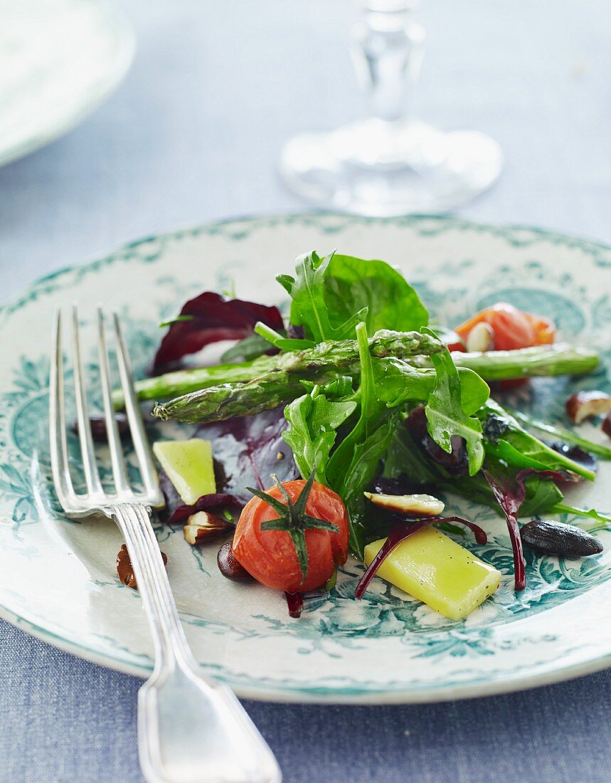 A mixed salad with green asparagus, lettuce, almonds and tomatoes