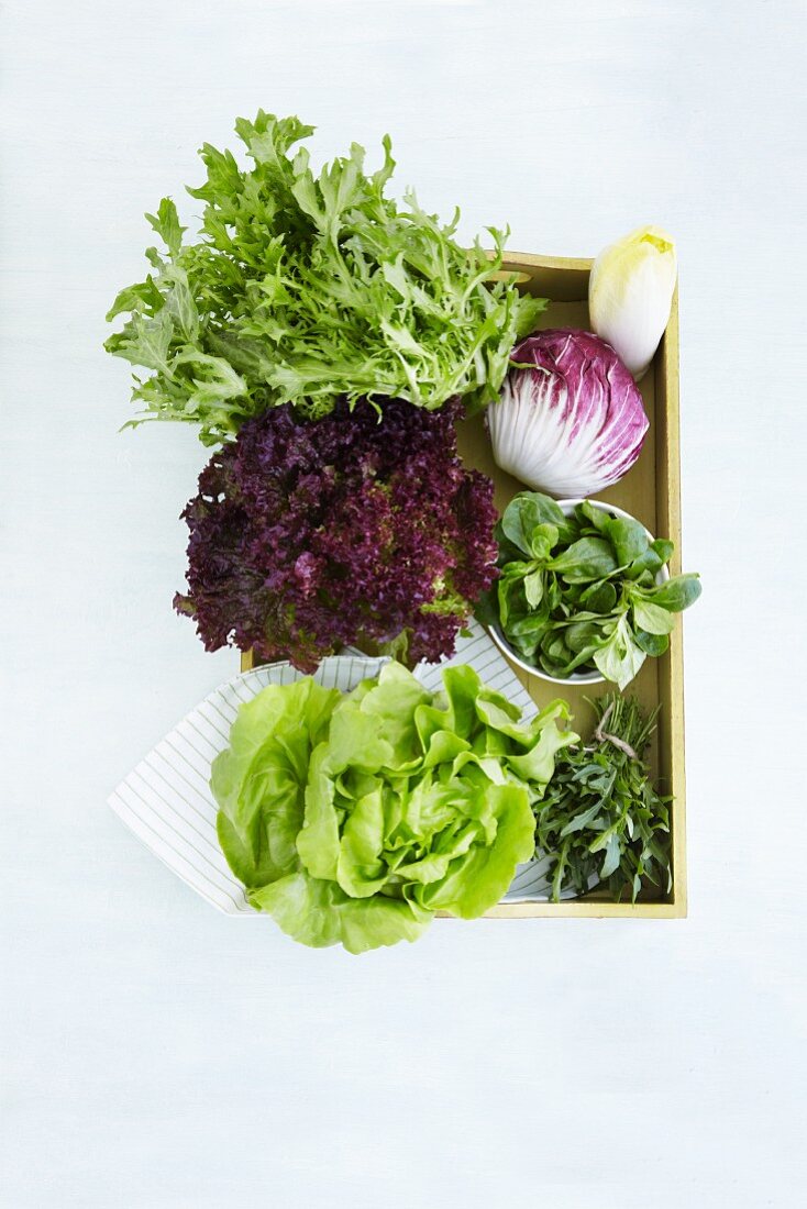 Various types of lettuce in a wooden crate (seen from above)