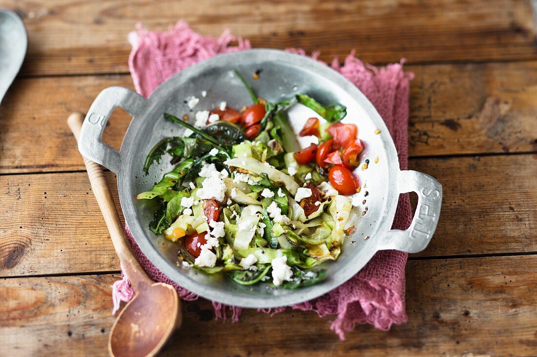 Stir-fried pointed cabbage with tomatoes and sheep's cheese