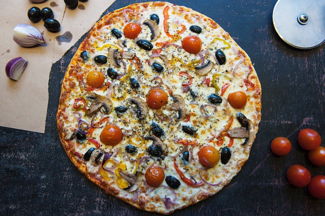 Pizza topped with cherry tomatoes, mushrooms, onions and olives