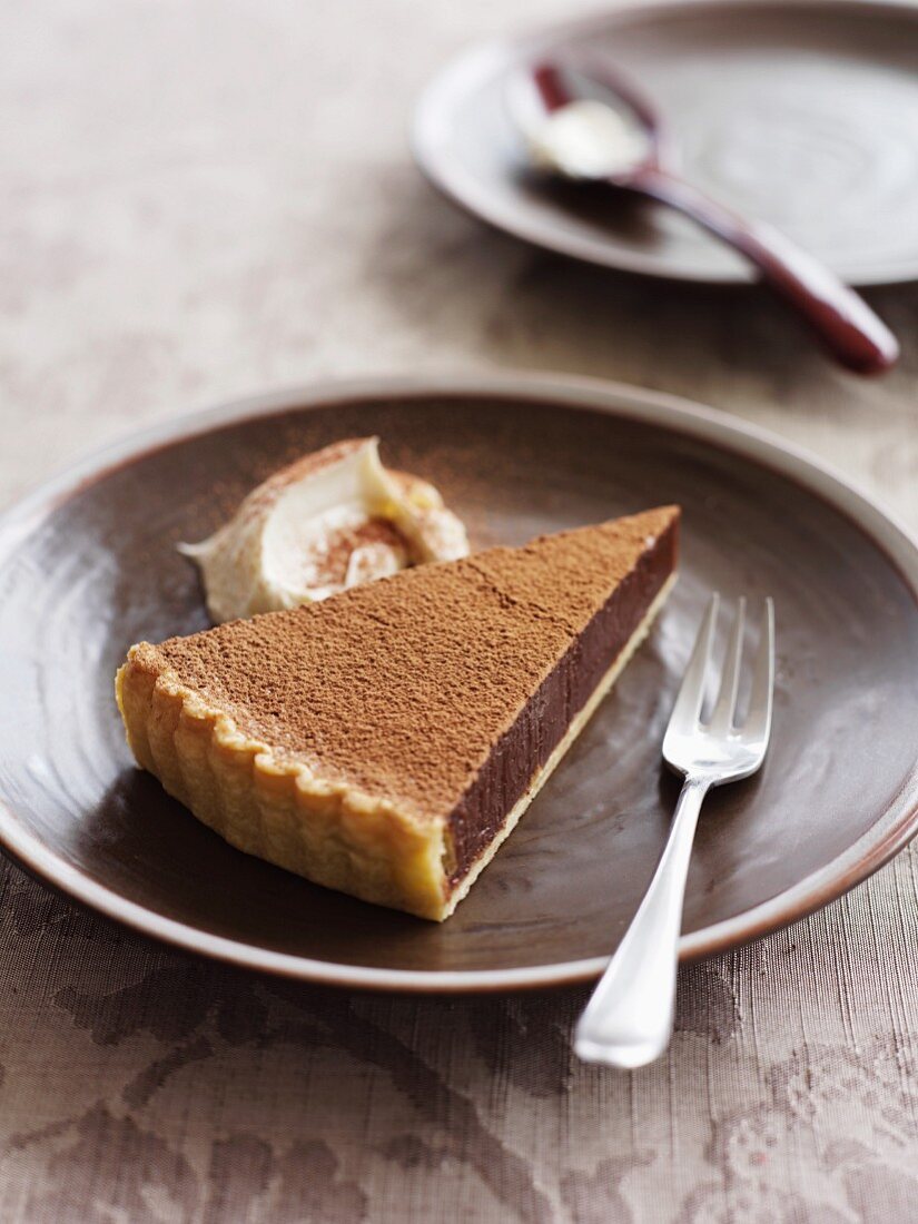 A slice of chocolate tart with cocoa powder