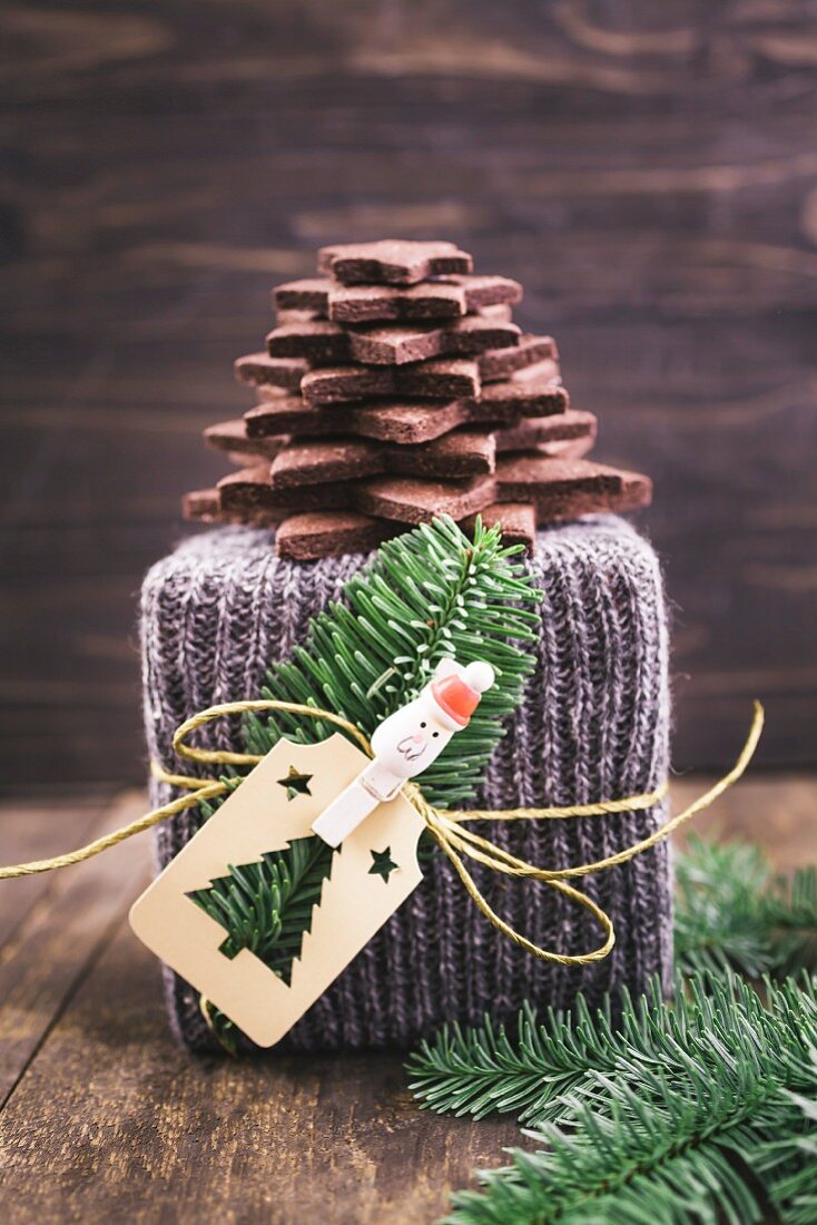 A Christmas gift wrapped in knitted gift wrap with a Christmas tree made of chocolate biscuits