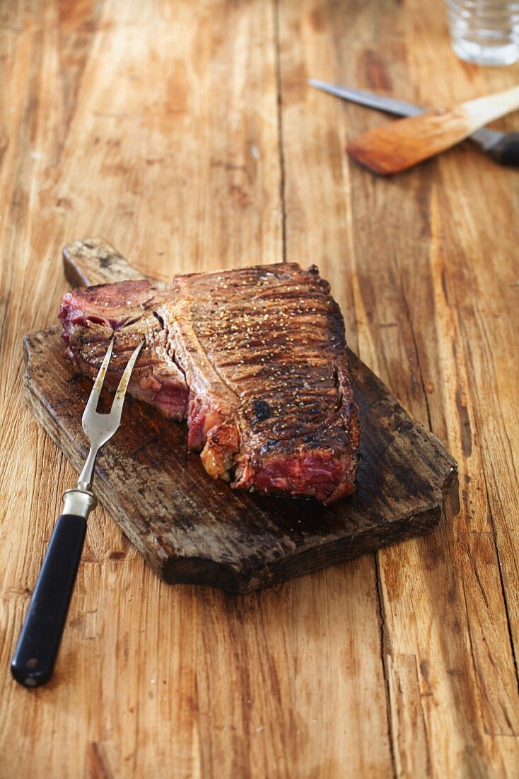 A grilled steak on a chopping board on a wooden table