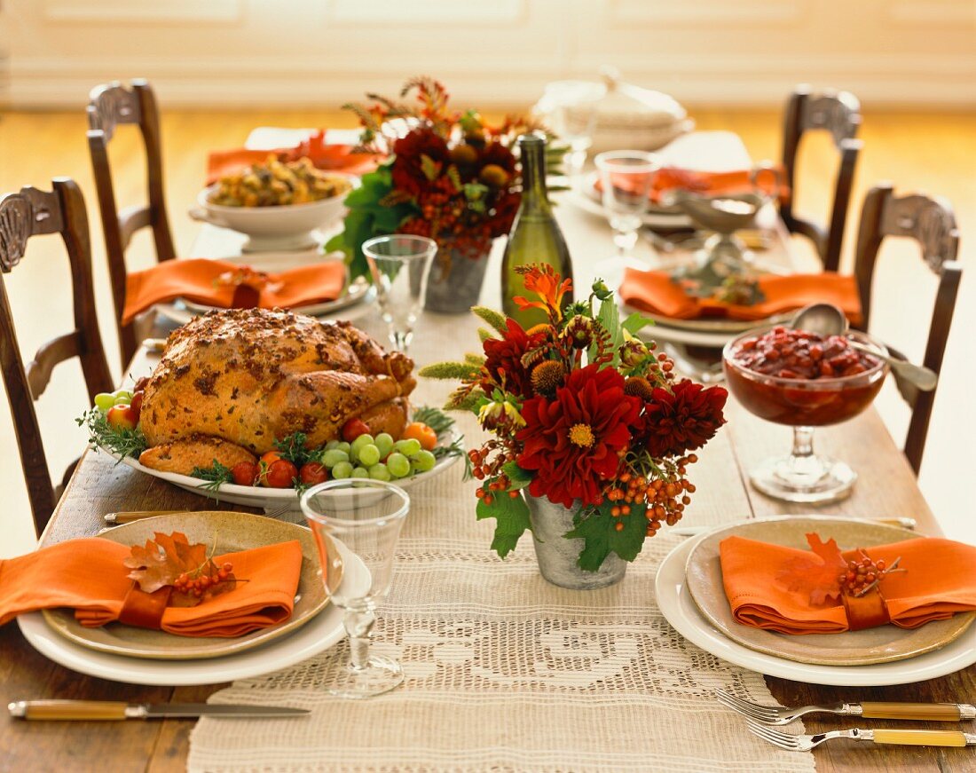 Roast turkey and cranberries on a table laid with autumnal decorations